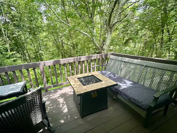 Deck seating around the propane fire table beneath the trees at Mountain Retreat