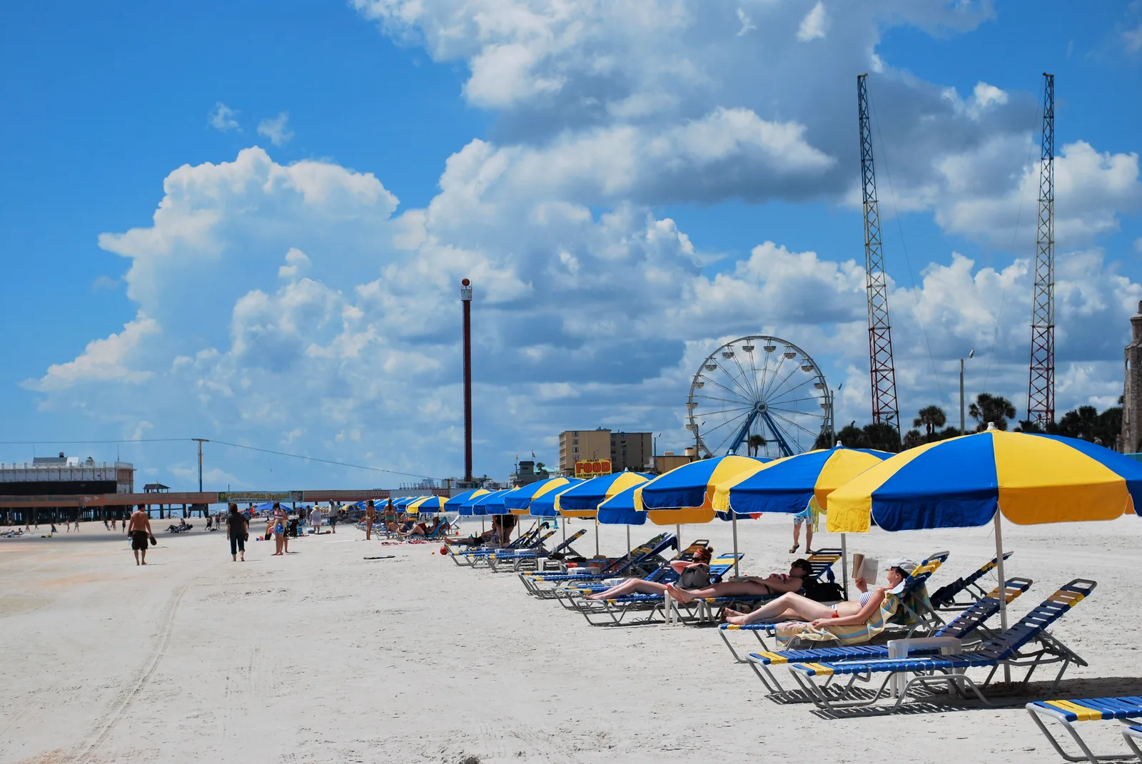 Beach umbrellas, lounge chairs, and the boardwalk Ferris wheel at Daytona Beach, Florida