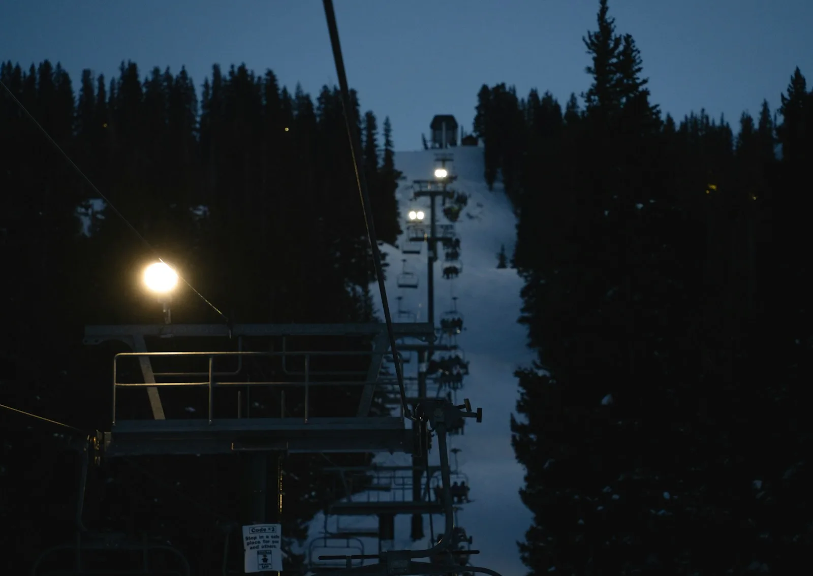 A chairlift ascending a floodlit slope during night skiing